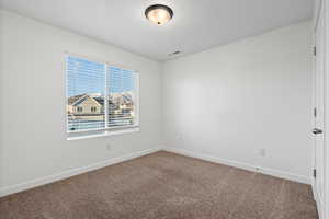 Carpeted empty room with visible vents and baseboards