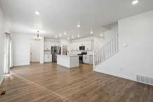 Unfurnished living room featuring light wood-style floors, visible vents, a chandelier, and a sink