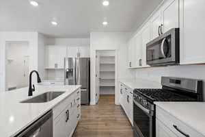 Kitchen with appliances with stainless steel finishes, light countertops, a sink, and wood finished floors