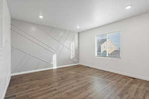 Empty room featuring baseboards, visible vents, wood finished floors, and recessed lighting