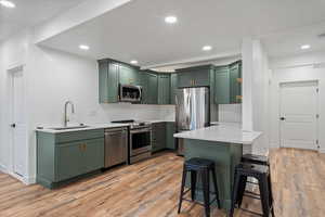 Kitchen featuring stainless steel appliances, a sink, and green cabinetry