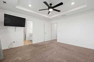 Unfurnished bedroom with baseboards, visible vents, a raised ceiling, and light colored carpet