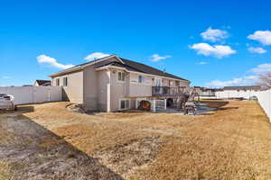 Rear view of house with a lawn, a fenced backyard, a wooden deck, a patio area, and stucco siding