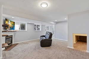 Sitting room featuring a textured ceiling, recessed lighting, a glass covered fireplace, and baseboards