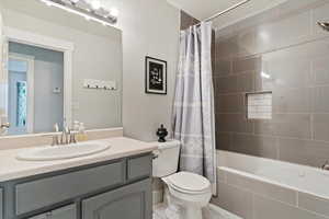 Bathroom featuring tiled shower / bath combo, toilet, and vanity