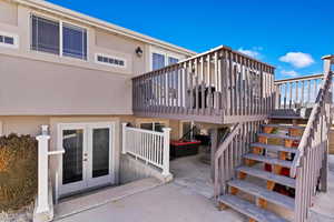 Exterior space with stucco siding, a wooden deck, stairway, and french doors