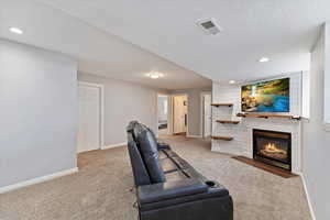 Carpeted living area with recessed lighting, visible vents, a fireplace with flush hearth, a textured ceiling, and baseboards