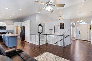 Living room with dark wood-type flooring, arched walkways, vaulted ceiling, and recessed lighting