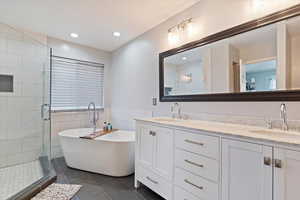 Full bathroom with double vanity, a soaking tub, a sink, and tile patterned flooring