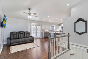 Living room with a decorative wall, recessed lighting, a ceiling fan, vaulted ceiling, and dark wood finished floors