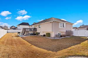 Rear view of house with a yard, a fenced backyard, a deck, and stucco siding