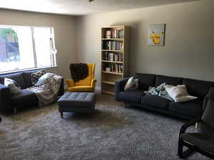 Living area with dark carpet and a textured ceiling