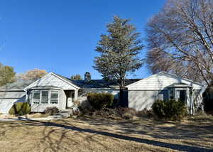 View of front of home with a front lawn, a chimney, an attached garage, and stucco siding