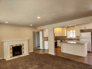 Kitchen with freestanding refrigerator, white cabinets, a kitchen island, and carpet flooring