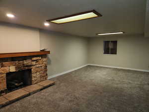 Unfurnished living room featuring baseboards, a fireplace, dark carpet, and recessed lighting