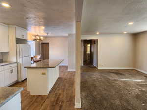 Kitchen featuring recessed lighting, an inviting chandelier, freestanding refrigerator, white cabinetry, and a kitchen island