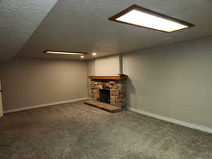 Finished basement with a textured ceiling, a fireplace, carpet flooring, and baseboards