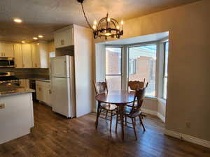 Dining space featuring a textured ceiling, recessed lighting, dark wood-style flooring, baseboards, and an inviting chandelier