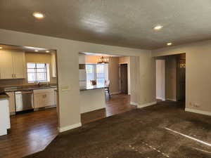 Kitchen featuring white cabinetry, stainless steel dishwasher, freestanding refrigerator, dark countertops, and pendant lighting