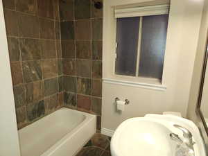 Full bath with washtub / shower combination, baseboards, and a sink