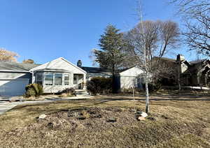 View of front of property with an attached garage, a chimney, and concrete driveway