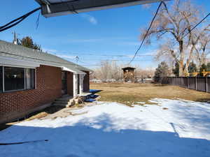 Yard layered in snow featuring a patio area and fence