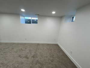 Basement featuring baseboards, visible vents, dark colored carpet, and recessed lighting