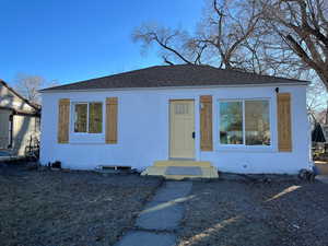 Bungalow-style house with a shingled roof and stucco siding