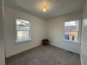 Carpeted empty room featuring baseboards and visible vents