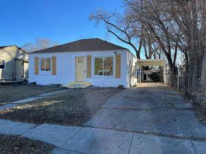 Bungalow with driveway, a shingled roof, an attached carport, and stucco siding