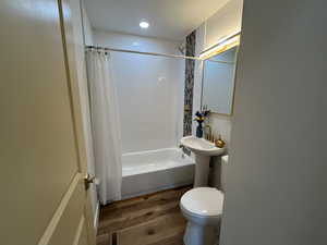 Full bath featuring shower / bath combination with curtain, visible vents, toilet, a sink, and wood finished floors