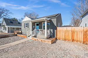 View of front facade featuring a porch, fence, and roof mounted solar panels