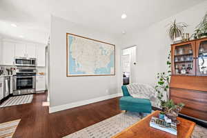 Sitting room with dark wood-type flooring, recessed lighting, and baseboards