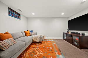 Living room featuring a textured ceiling, recessed lighting, visible vents, baseboards, and carpet