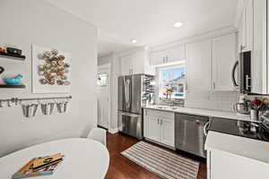 Kitchen with white cabinetry, appliances with stainless steel finishes, decorative backsplash, and a sink