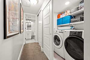 Washroom with washer and clothes dryer, light colored carpet, visible vents, laundry area, and baseboards