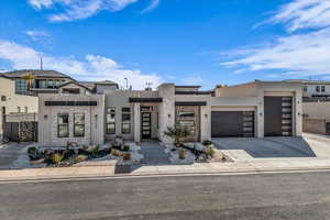 Contemporary house featuring driveway, stone siding, a garage, and stucco siding