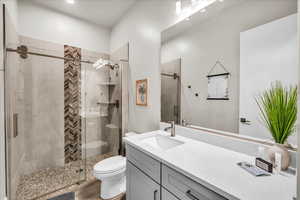 Bathroom with vanity, a shower stall, and toilet