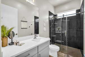 Full bath with toilet, a stall shower, wood finished floors, and vanity