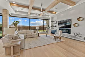 Living room featuring light wood-style floors, a high end fireplace, visible vents, and coffered ceiling