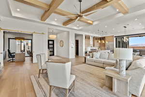 Living area with light wood-type flooring, ceiling fan, a barn door, and coffered ceiling