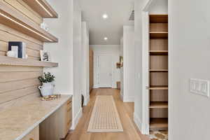 Hallway with light wood-style flooring, visible vents, baseboards, and recessed lighting