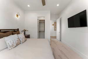 Bedroom featuring a walk in closet, recessed lighting, a ceiling fan, light carpet, and baseboards