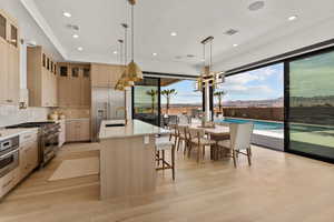 Kitchen featuring decorative light fixtures, visible vents, high quality appliances, an island with sink, and glass insert cabinets