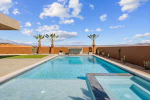 View of pool with a pool with connected hot tub, a patio area, a fenced backyard, and a mountain view