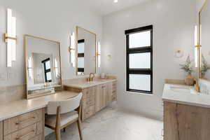 Full bath with marble finish floor, two vanities, a sink, and recessed lighting