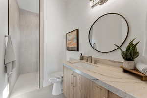 Bathroom featuring toilet, tile patterned floors, a walk in shower, and vanity