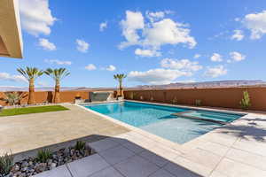 View of swimming pool with a pool with connected hot tub, a fenced backyard, a patio, and a mountain view