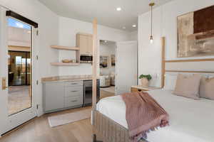 Bedroom with light wood-style floors, recessed lighting, multiple windows, and freestanding refrigerator