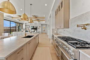 Kitchen with open floor plan, stainless steel appliances, light brown cabinetry, and a sink